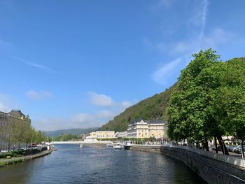 Scenic view of river by buildings against sky