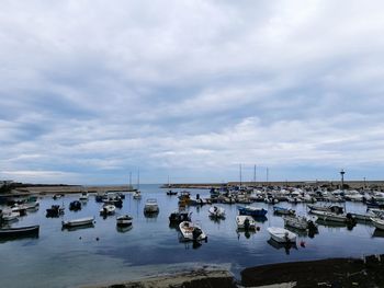 Sailboats moored in sea against sky