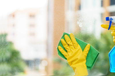 Cropped hands of person cleaning window