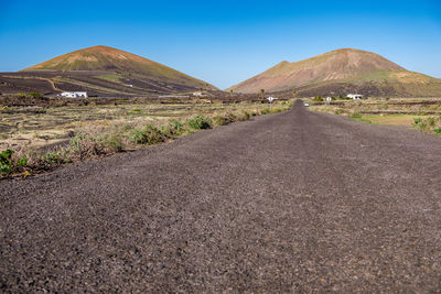 Road leading towards mountains against sky