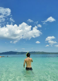 Rear view of shirtless man in sea against sky