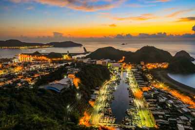 High angle view of illuminated city against sky at sunset