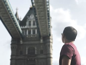 Low angle view of young man looking at tower bridge