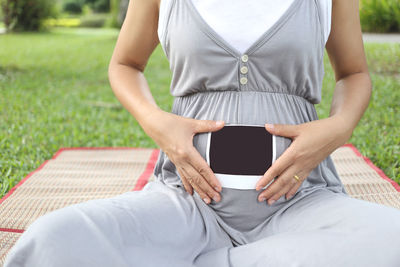 Midsection of woman holding while sitting outdoors