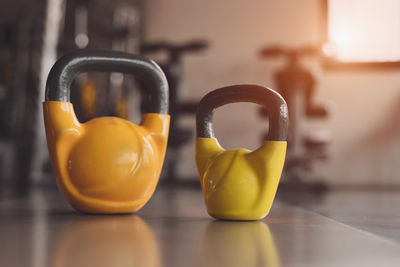 Close-up of yellow kettlebells on floor at gym