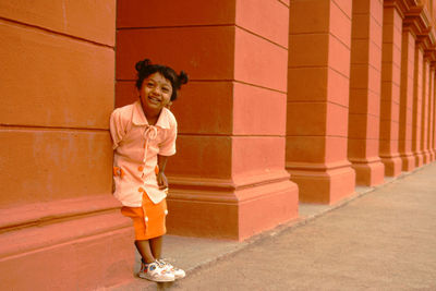 Portrait of smiling girl standing against brick wall