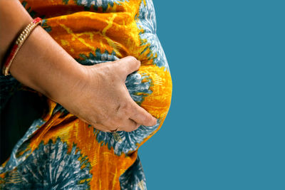 Midsection of woman holding gift against blue background