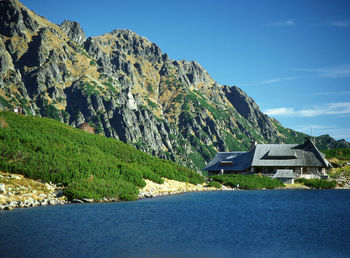 View of rocky mountains in front of houses against blue sky