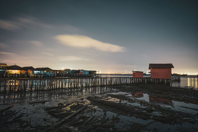 Scenic view of beach by buildings against sky during sunset