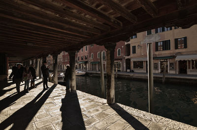 People in canal amidst buildings in city