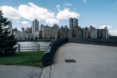 Modern buildings by river against sky in city