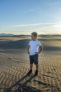 Full length of boy standing on sand against sky