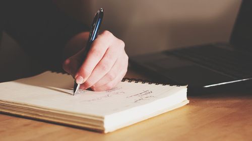 Cropped hand of person writing in diary