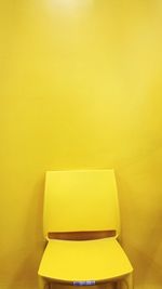 Empty chair against yellow wall