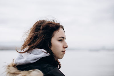 Teenager girl looking at the sea. cold windy weather