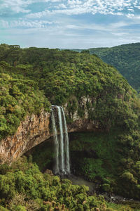 Caracol waterfall falling from rocky cliff in a canyon covered by forest near canela, brazil.