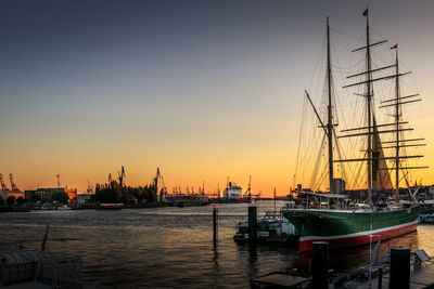 Boats moored in harbor during sunset