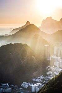 Aerial view of buildings and mountains against sky during sunset