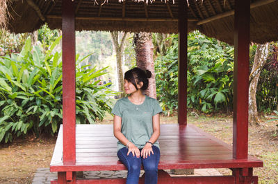 Full length of young woman standing against plants