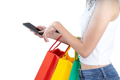 Midsection of woman using mobile phone against white background