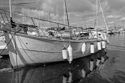 Fishing boats moored at harbor against sky