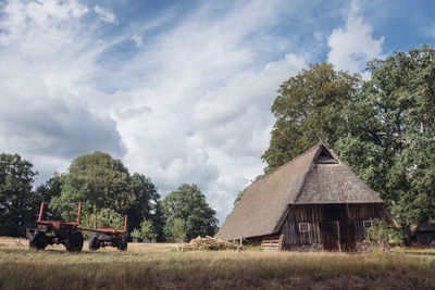 Trees and houses on field against sky