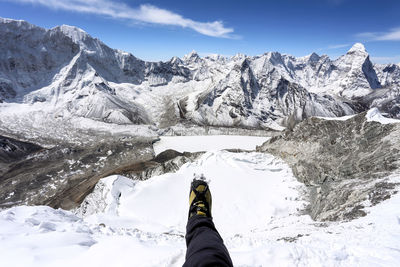 Low section of person on snowcapped mountains against sky