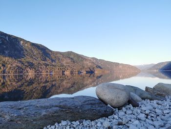 Scenic view of lake and mountains against clear blue sky