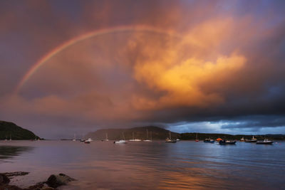 Scenic view of rainbow over sea against sky