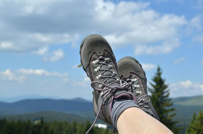 Low section of person relaxing against sky