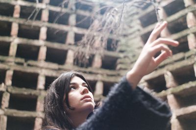 Low angle view of thoughtful woman standing against wall