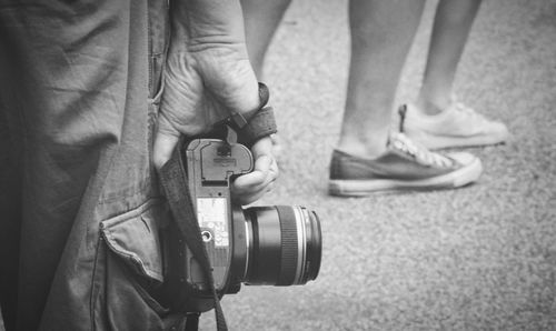 Midsection of man with camera standing on street