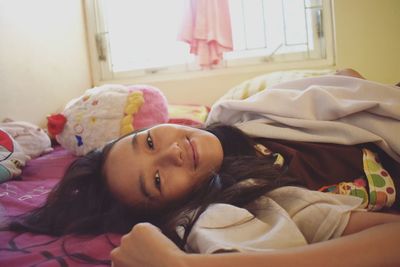 Portrait of woman lying on bed at home