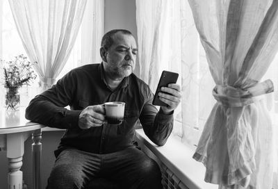 Full length of man using mobile phone at home