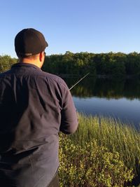 Rear view of man fishing by lake