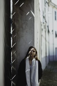 Portrait of woman standing against wall