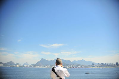 Rear view of woman by sea against sky