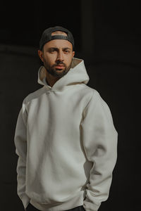 Portrait of man standing against black background