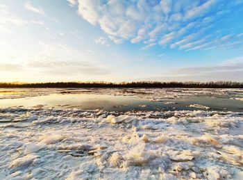 Scenic view of frozen river against sky during sunset