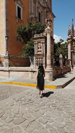 Rear view of woman walking on street amidst buildings