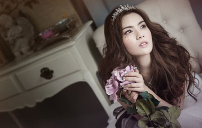 Beautiful young bride with rose wearing tiara at home