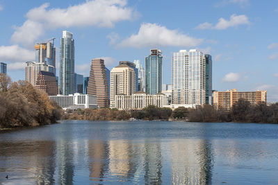 Buildings by river against sky