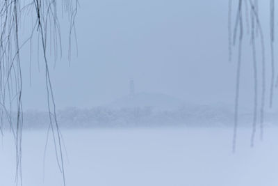 Snow covered electricity pylon against sky