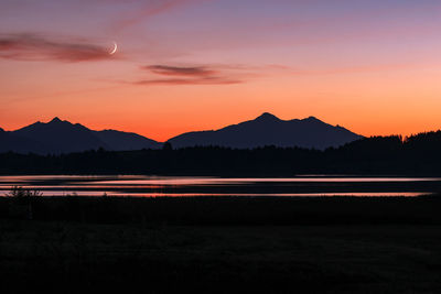 Scenic view of silhouette mountains against romantic sky at sunset