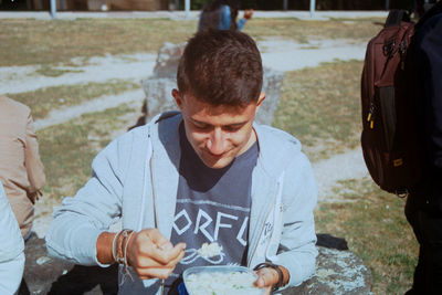 Young man eating food on field