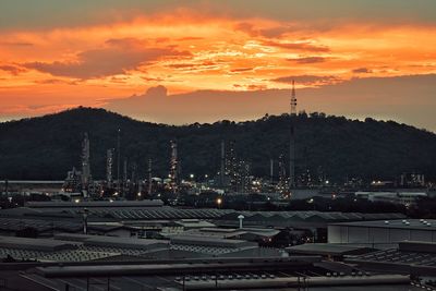 Sailboats in city against orange sky