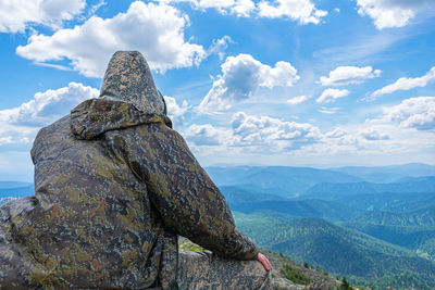 Rear view of person on rock against sky