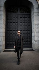 Full length of young man standing against wall