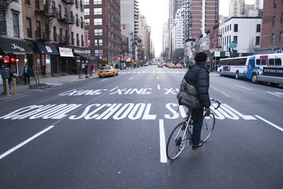 Man riding bicycle on road amidst buildings in city