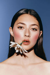 Portrait of beautiful young woman against blue background